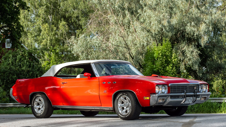 Red Buick Skylark convertible on the road with trees in the background
