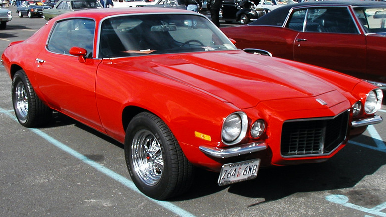 Red second-generation Chevrolet Camaro in a parking lot during a car show