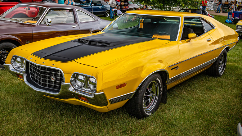 Yellow Early 1970s Ford Gran Torino parked on grass at a car show