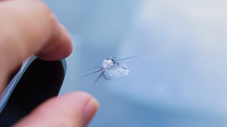 A closeup image of a person repairing a cracked windshield.