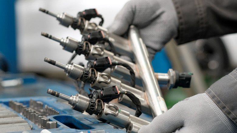 Mechanic handling a rail of fuel injectors.