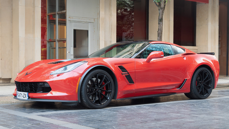 Front 3/4 view of a red 2017 Chevrolet Corvette (C7) Grand Sport (Z15) parked in front of a residential building in Spain.