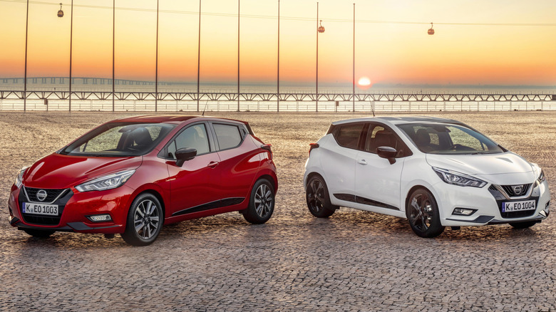 A pair of Nissan Micra vehicles sit parked.