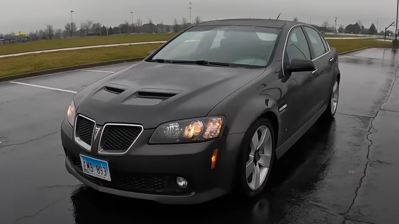A black-gray Pontiac G8 parked in a wet parking lot.
