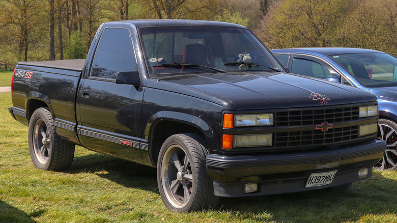Black 1990 Chevrolet 454 SS pickup truck right front three-quarter view parked on grass with trees in background
