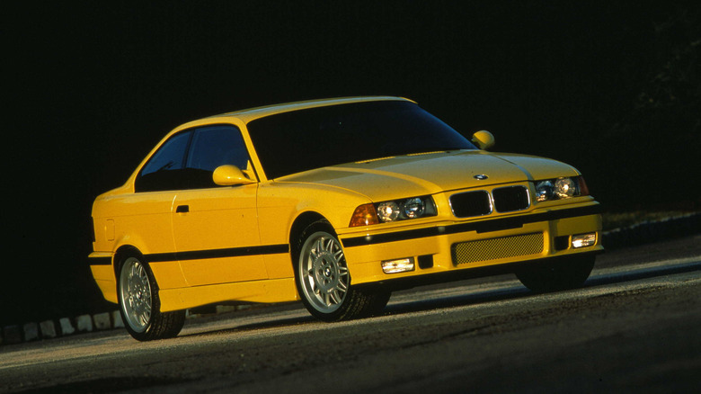 Yellow 1995 BMW M3 coupe right front three-quarter view in low-angle sunlight