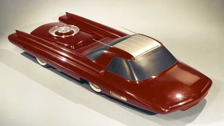 The metallic red 1958 Ford Nucleon scale-model concept car, displaying its futuristic forward-cab design, atomic reactor capsule pod over the rear axle, and finned rear fenders.