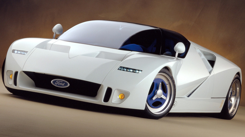 The white 1995 Ford GT90 supercar concept, featuring angular New Edge styling, sharp triangular side vents, a low-slung nose with central Ford oval badge, and blue three-spoke wheels.