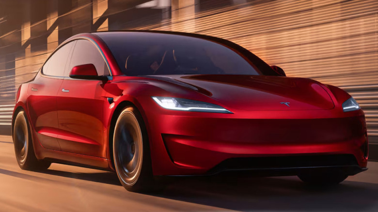 A red 2025 Tesla Model 3 Performance on a racetrack.