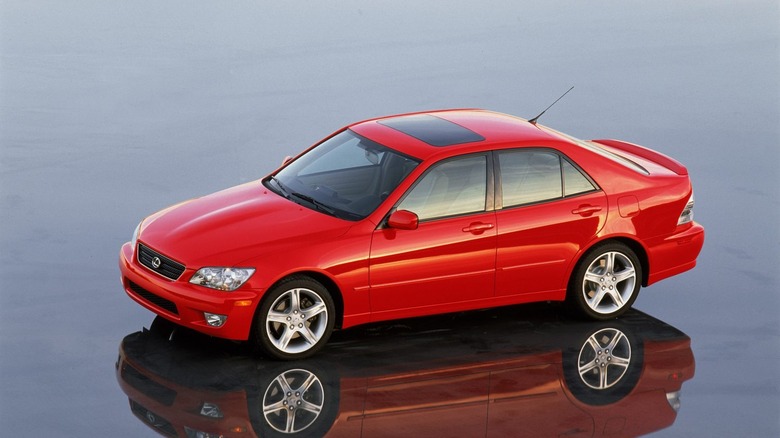 Red Lexus IS300 pictured on reflective surface.