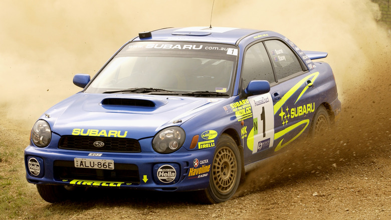 2002 Subaru Impreza WRX rally car sliding a dirt corner.
