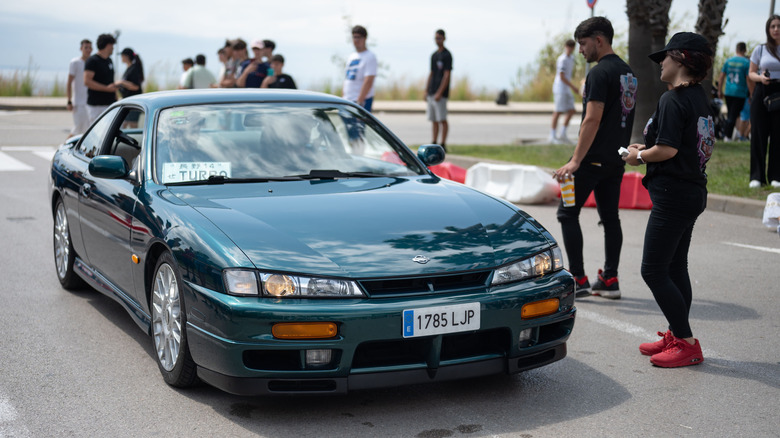 A dark green Nissan Silvia K's (S14) coupe at a car meet