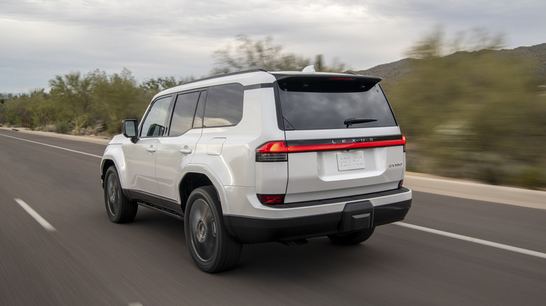 A white Lexus GX550 drives down the road.
