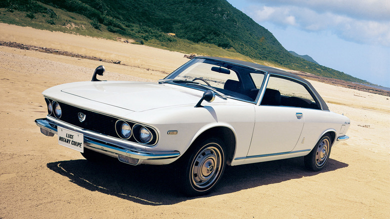 A white Mazda Luce Rotary Coupe on sandy terrain