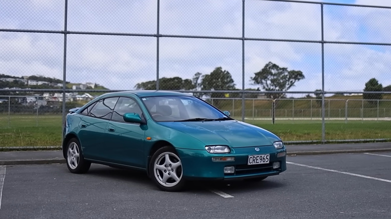 A green Mazda Lantis Type R in a parking lot