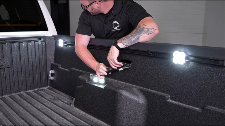 A mechanic installing lights in a Toyota Tacoma's bed.