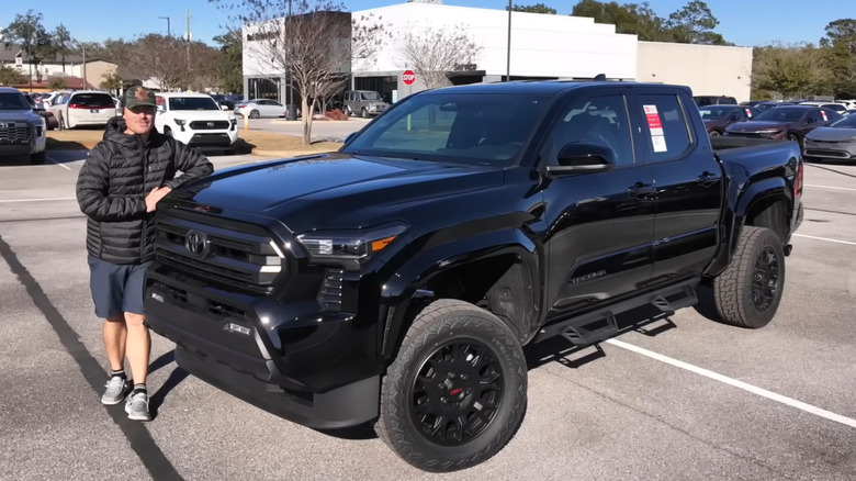A man standing next to a Toyota Tacoma with a TRD lift kit installed.