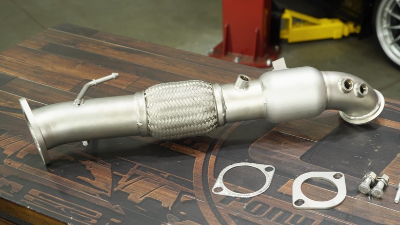 A CJ Pony Parts high-flow catted downpipe for a Ford Focus ST sitting on a wooden bench