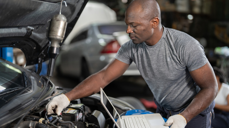 This is a technician performing diagnostic testing and performance tuning on a vehicle with a laptop.