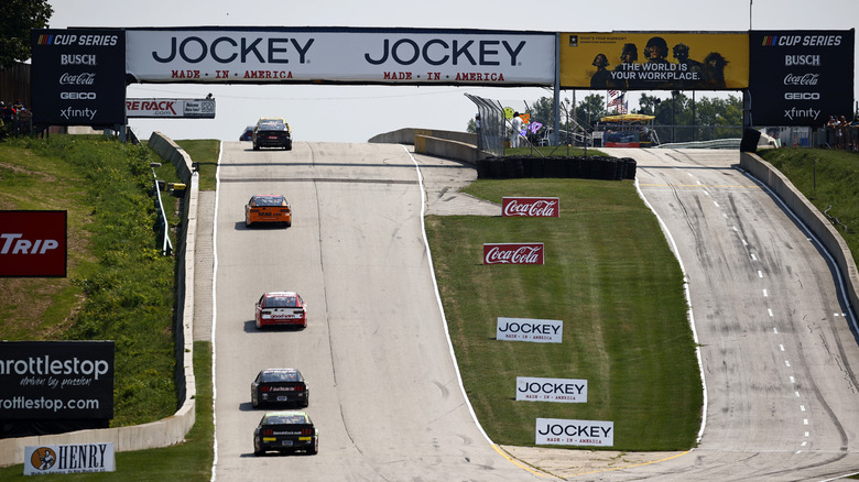 An elevation change is evident as cars race on the Road America course.