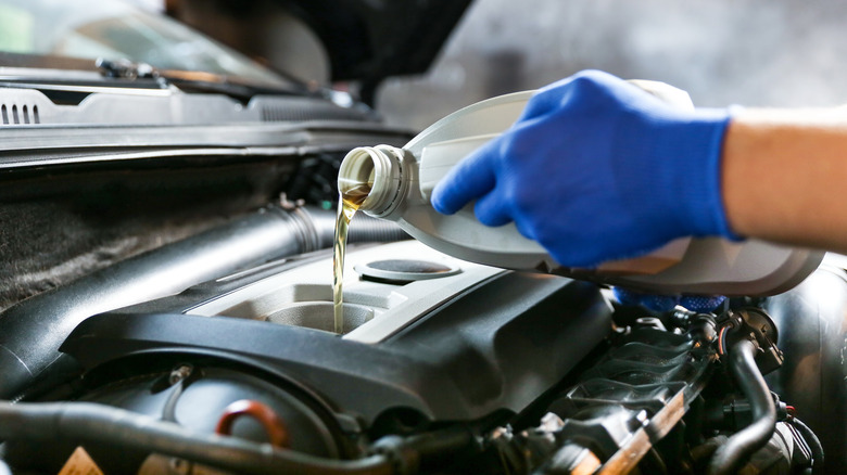 Mechanic filling up engine with oil.