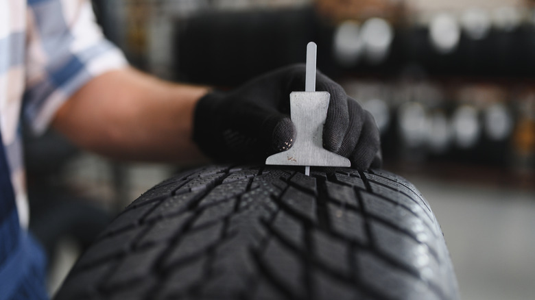 Mechanic checking tire tread depth.
