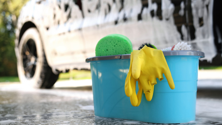 Car wash supplies next to a soapy car.