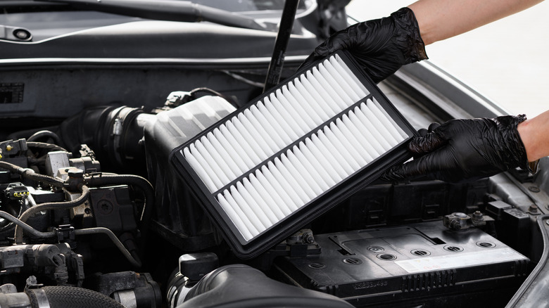 Mechanic holding engine air filter.