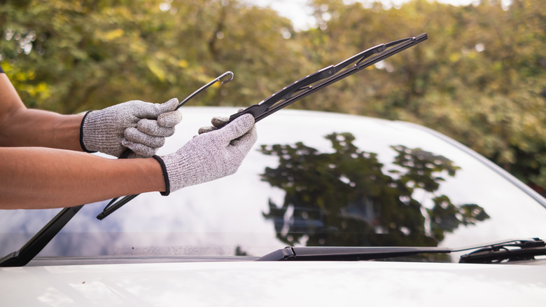 Person attaching wiper blade to car.
