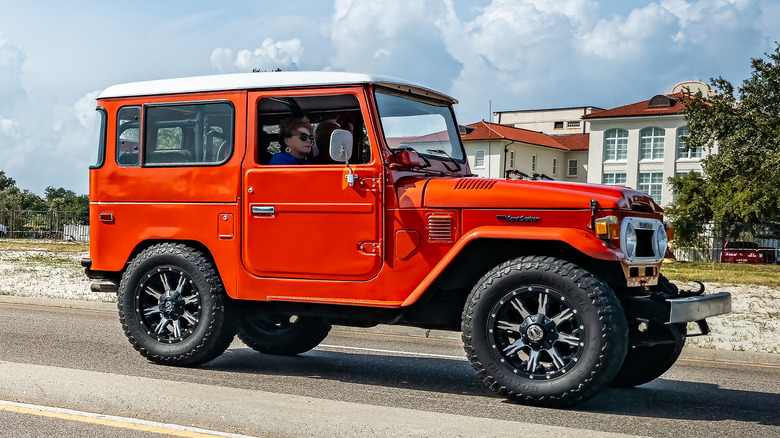A reddish 1970s two-door Toyota Land Cruiser connected nan road.