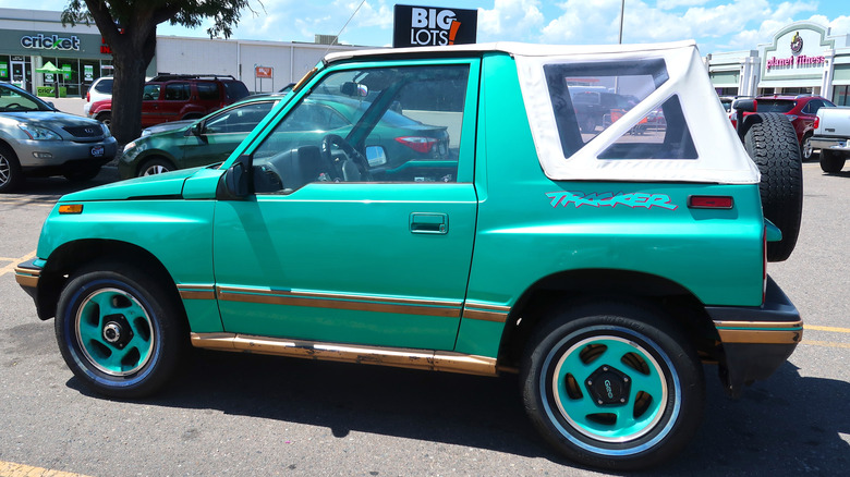A teal Chevrolet Tracker is in a parking lot in front of a Big Lots, a Cricket Wireless store, and a Planet Fitness.