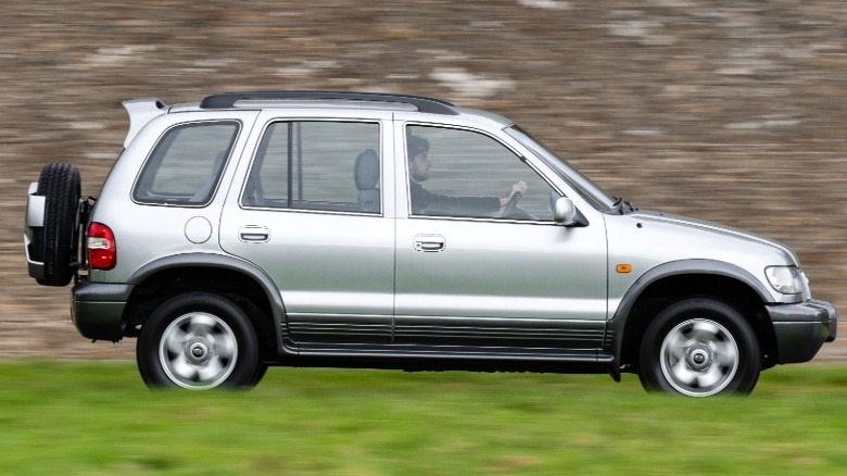 A silver Kia Sportage driving on grass.