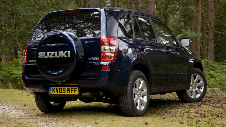 A dark blue Suzuki Grand Vitara is parked in the woods.