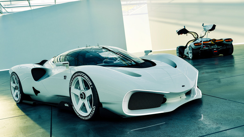 A white Nilu27 hypercar parked inside a spacious, modern showroom featuring a white industrial sawtooth skylight ceiling.