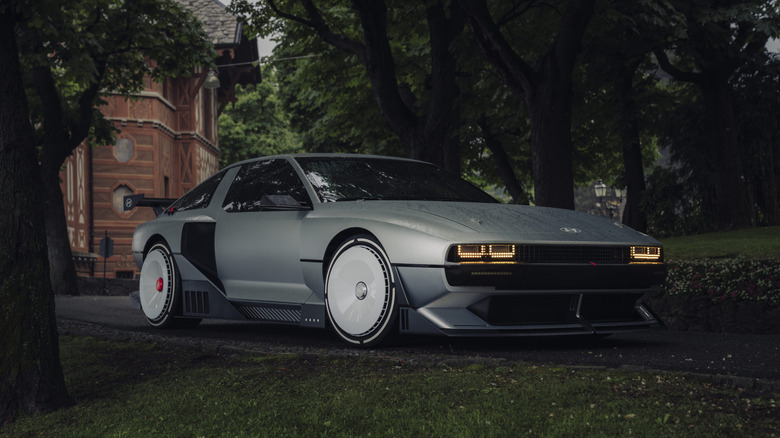 A matte silver-gray Hyundai N Vision 74 concept car parked on a damp asphalt pathway, captured from a low front-three-quarter angle.