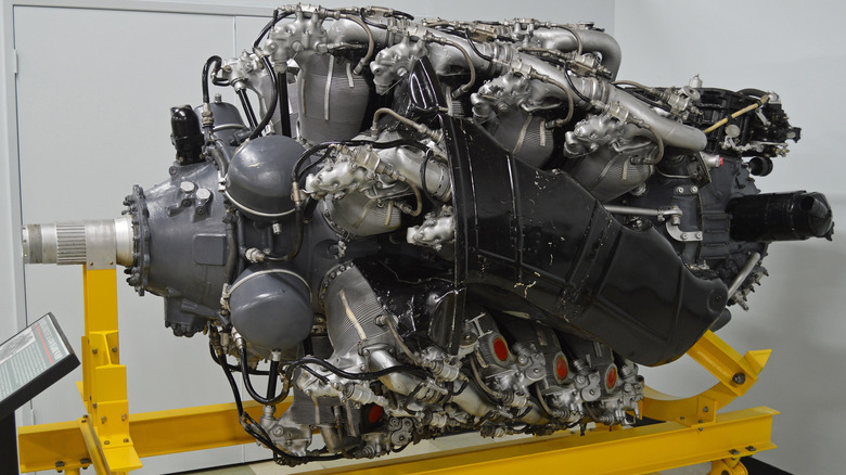 A Pratt & Whitney R-4360 "Wasp Major" air-cooled radial engine displayed on a bright yellow maintenance stand in a museum.