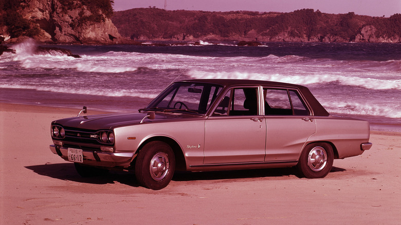 1969 Nissan 2000GT against an ocean background.