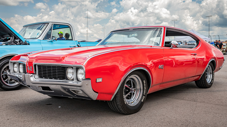 A red 1969 Oldsmobile 442 parked in a car show lot.