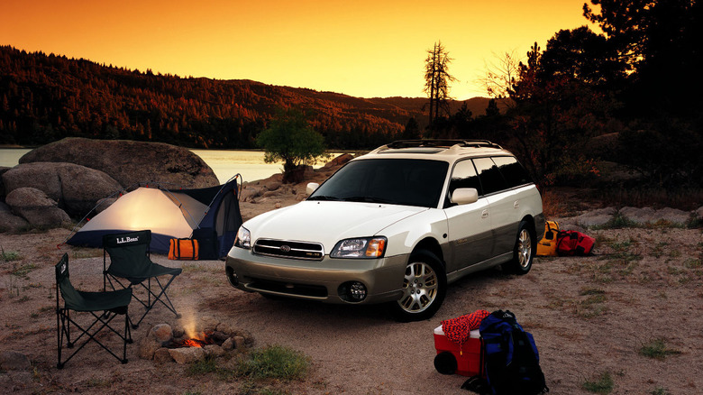 A white Subaru Outback in an outdoor camping scene.