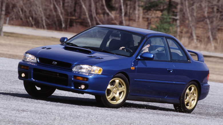 A 1993 Subaru Impreza WRX driving a gravel road course.