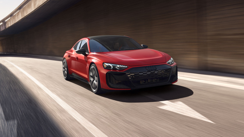 Red Audi RS e-tron GT driving along a curved highway under an overpass.
