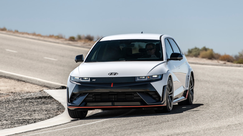 Front view of a white Hyundai Ioniq 5 N electric hot hatch cornering on a winding road.