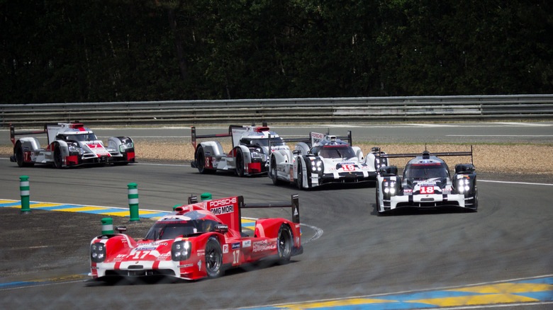 Race cars round a corner toward the camera at the 2015 24 Hours of LeMans