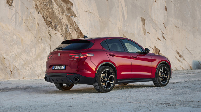 Red 2023 Alfa Romeo Stelvio SUV right rear three-quarter view parked in front of rock-faced cliff
