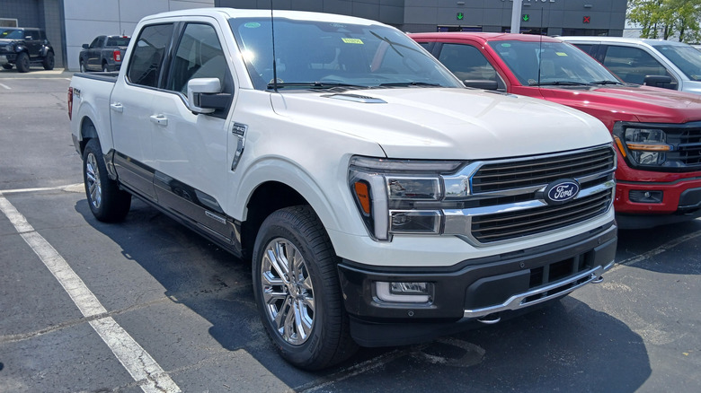 White 2024 Ford F-150 King Ranch pickup truck right front three-quarter view parked outdoors at a dealership