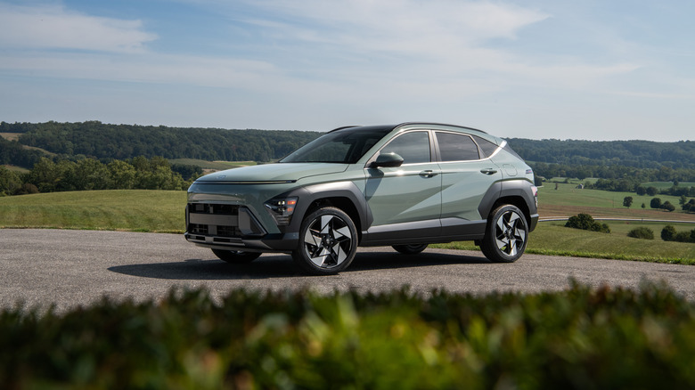Green 2026 Hyundai Kona SUV left front three-quarter view parked in front of rolling rural hillsides
