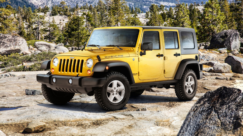 Yellow 2007 Jeep Wrangler Rubicon SUV left front three-quarter view parked in rocky landscape