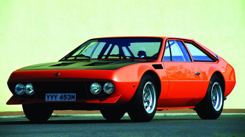 Orange 1973 thru 1976 Lamborghini Jarama sports car left front three-quarter view parked against a yellow sky background