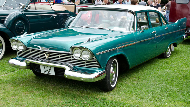 Green 1958 Plymouth Savoy sedan left front three-quarter view parked on grass at car show