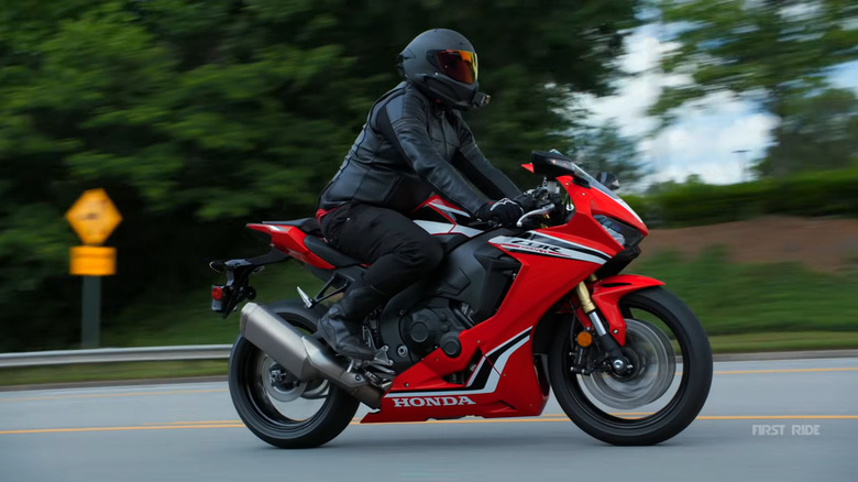A red Honda CBR1000RR is ridden by a man in black gear.